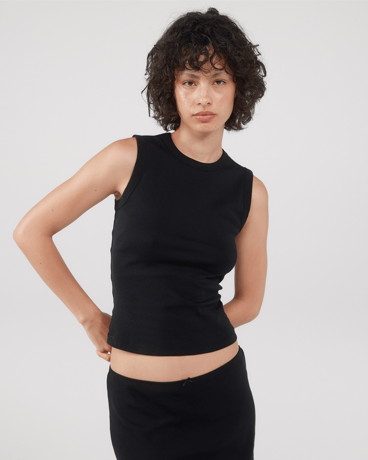 Person wearing a black sleeveless top and black skirt.