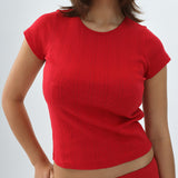 Person wearing a red top on a plain background