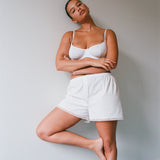Woman wearing a white bra and shorts against a plain background