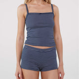 A model wearing a matching two-piece loungewear set consisting of a navy blue and white striped camisole top and matching shorts, photographed against a solid light gray background.
