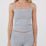 A woman modeling a matching two-piece loungewear set consisting of a square-neck tank top and shorts, both featuring thin horizontal navy and white stripes. The top has a small white bow on the center chest.