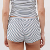 Rear view of a model wearing a matching two-piece lounge set with thin navy blue horizontal stripes on a white base, consisting of a cropped tank top and shorts.
