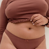 Person wearing a brown long-sleeve top and matching underwear set against a neutral background