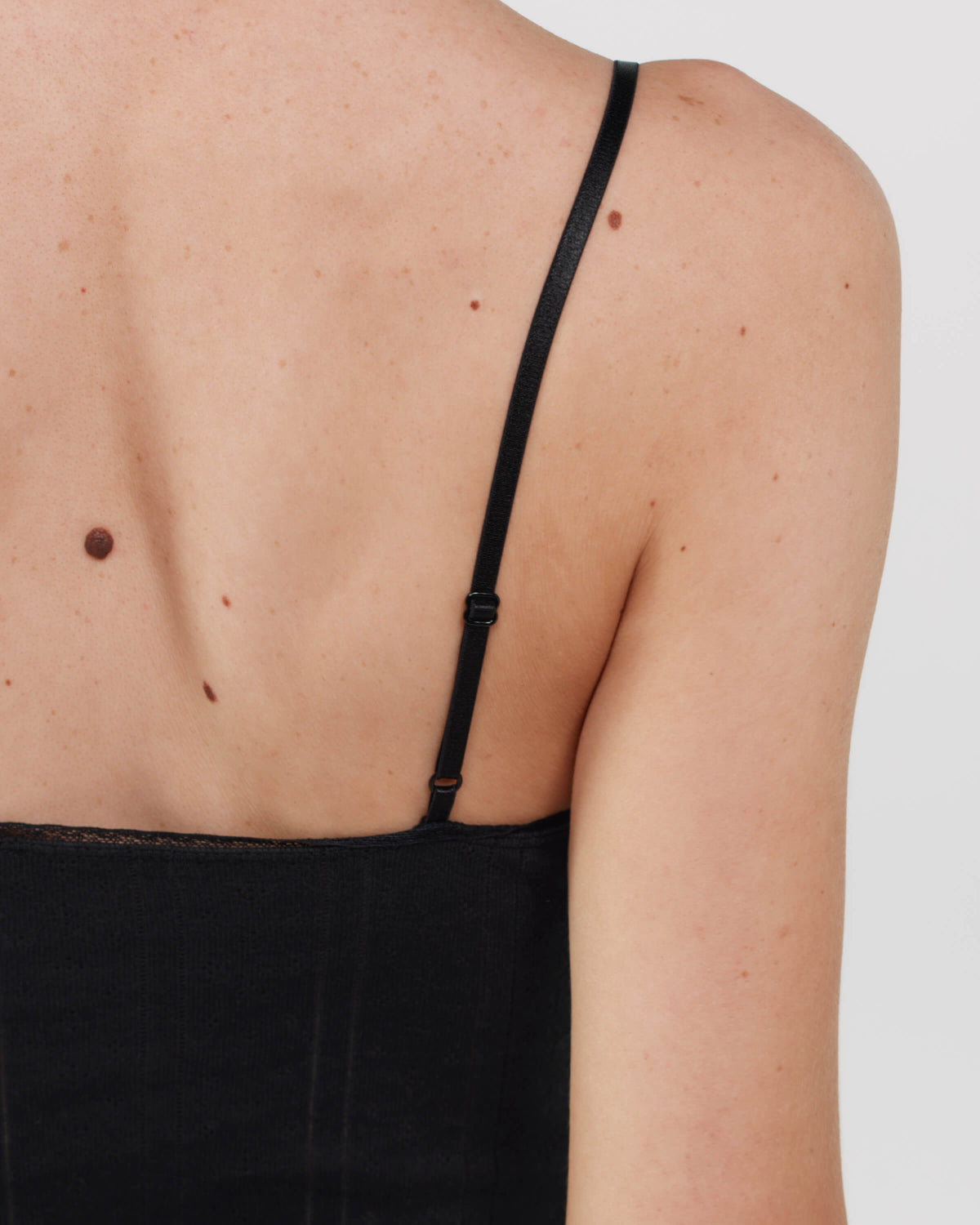 Black cami dress worn by a person on a plain background