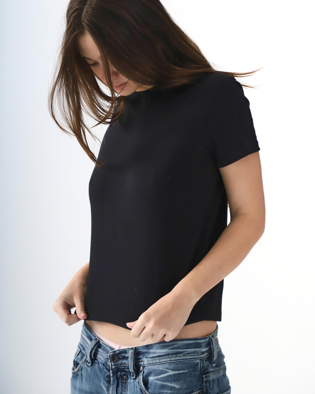Person wearing a black t-shirt and blue jeans on a white background