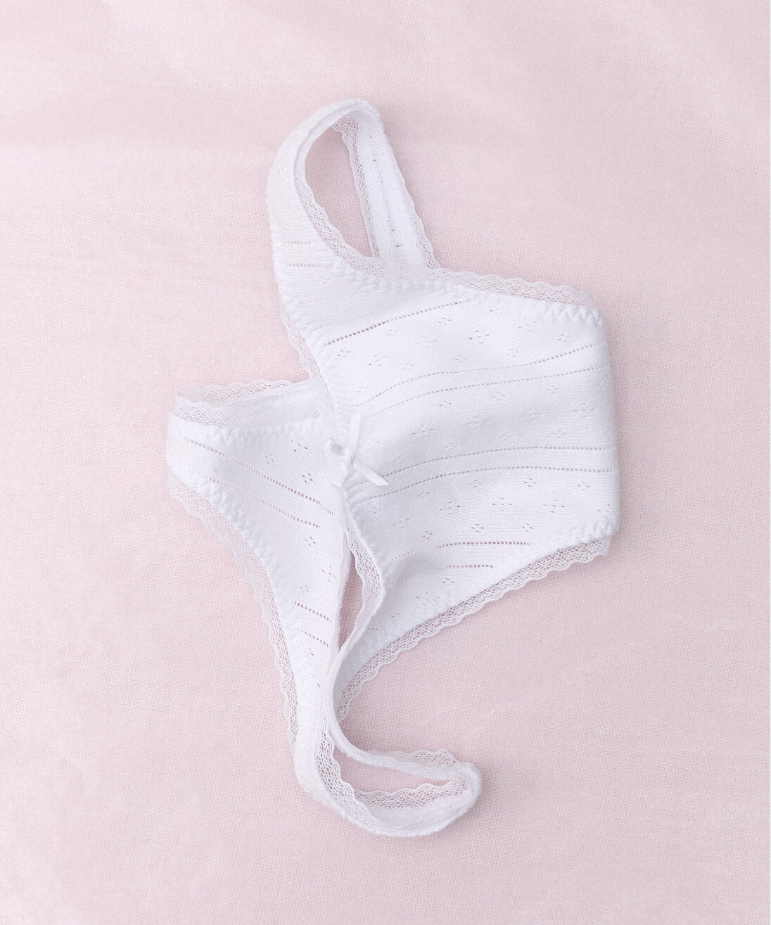 White lace thong on a light pink background