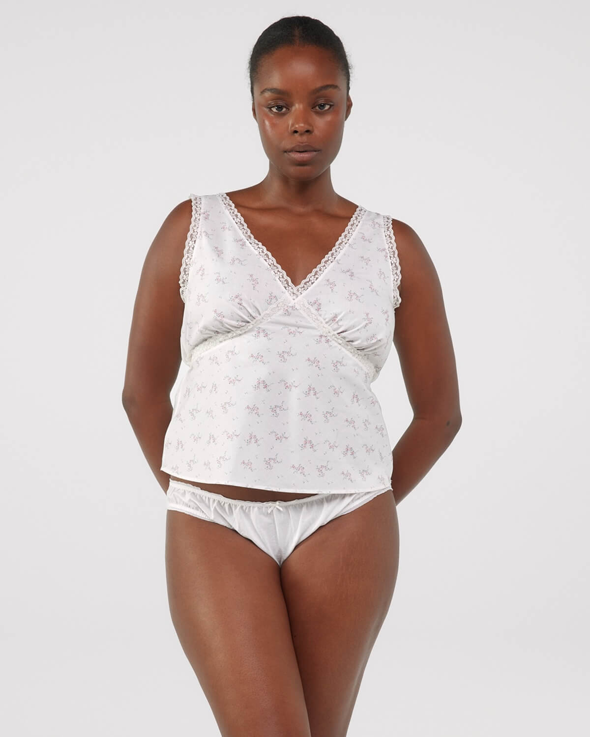 Woman wearing a white lace lingerie set on a plain background