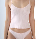 Woman wearing a light pink top and underwear set on a plain background