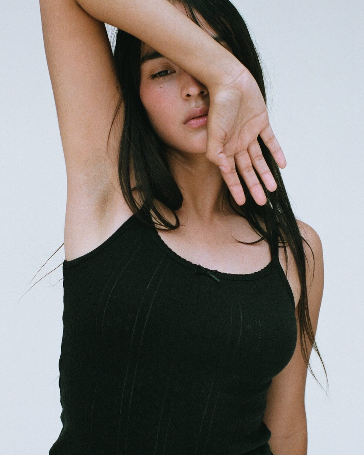 Woman wearing a black tank top against a plain background