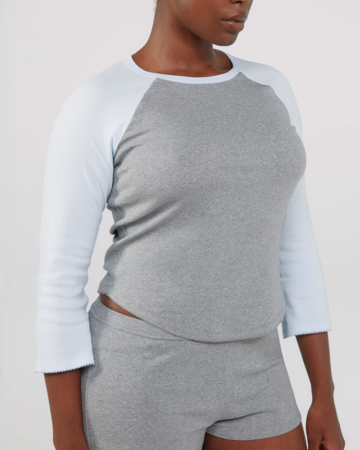 Person wearing a gray and white long-sleeve top with matching shorts on a plain background