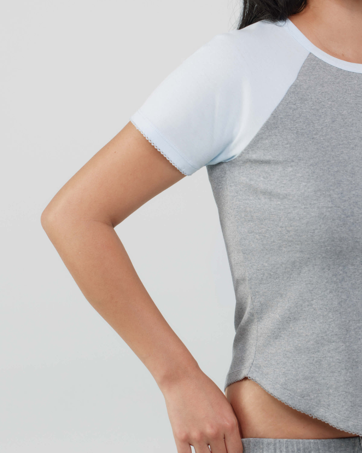 Gray and blue crop top worn by a person on a light gray background