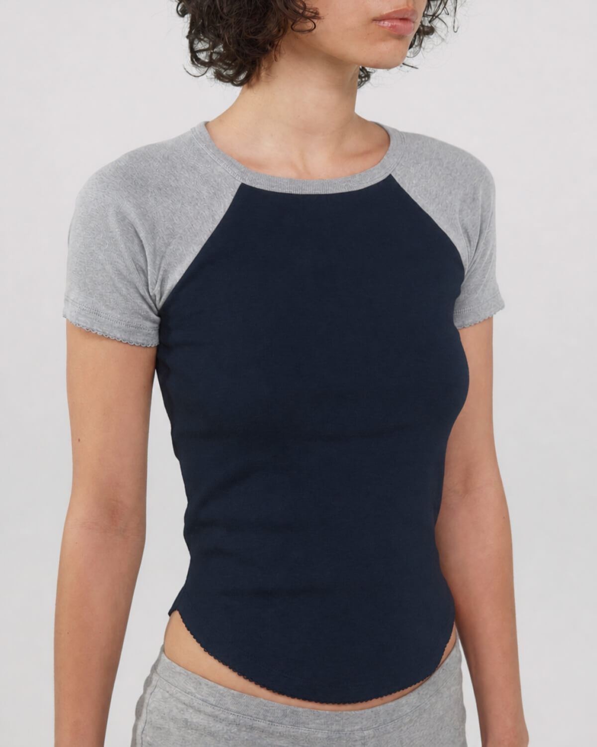 Person wearing a navy and gray baseball shirt on a plain background