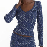 Woman wearing a blue patterned long-sleeve top and shorts set on a white background