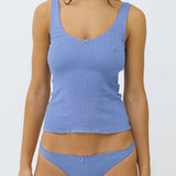 Woman wearing a blue tank and thong set on a white background