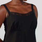 Black slip dress with lace detailing on a plain background