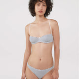 A model wearing a bra and thong with a navy and white horizontal stripe pattern, photographed against a solid light gray background.