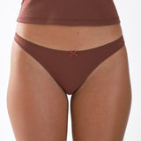Brown thong worn by a person on a white background