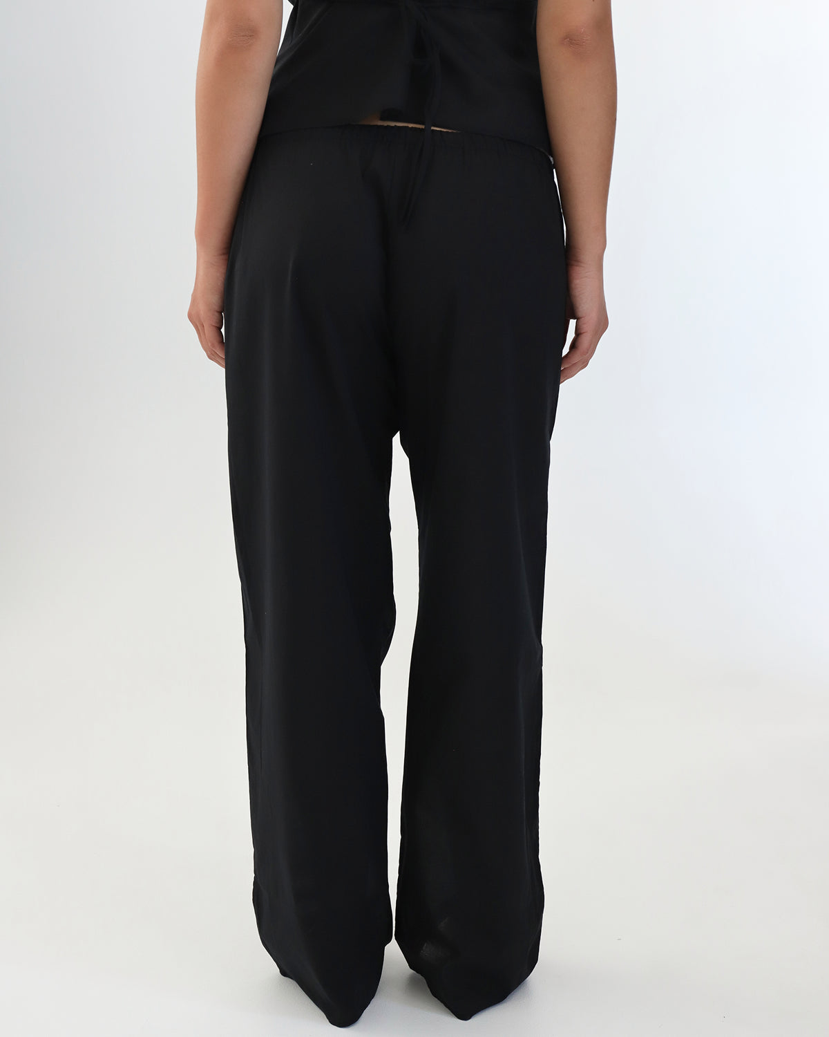 Person wearing black wide-leg pants on a white background