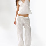 Woman wearing a white sleeveless top and pants on a white background